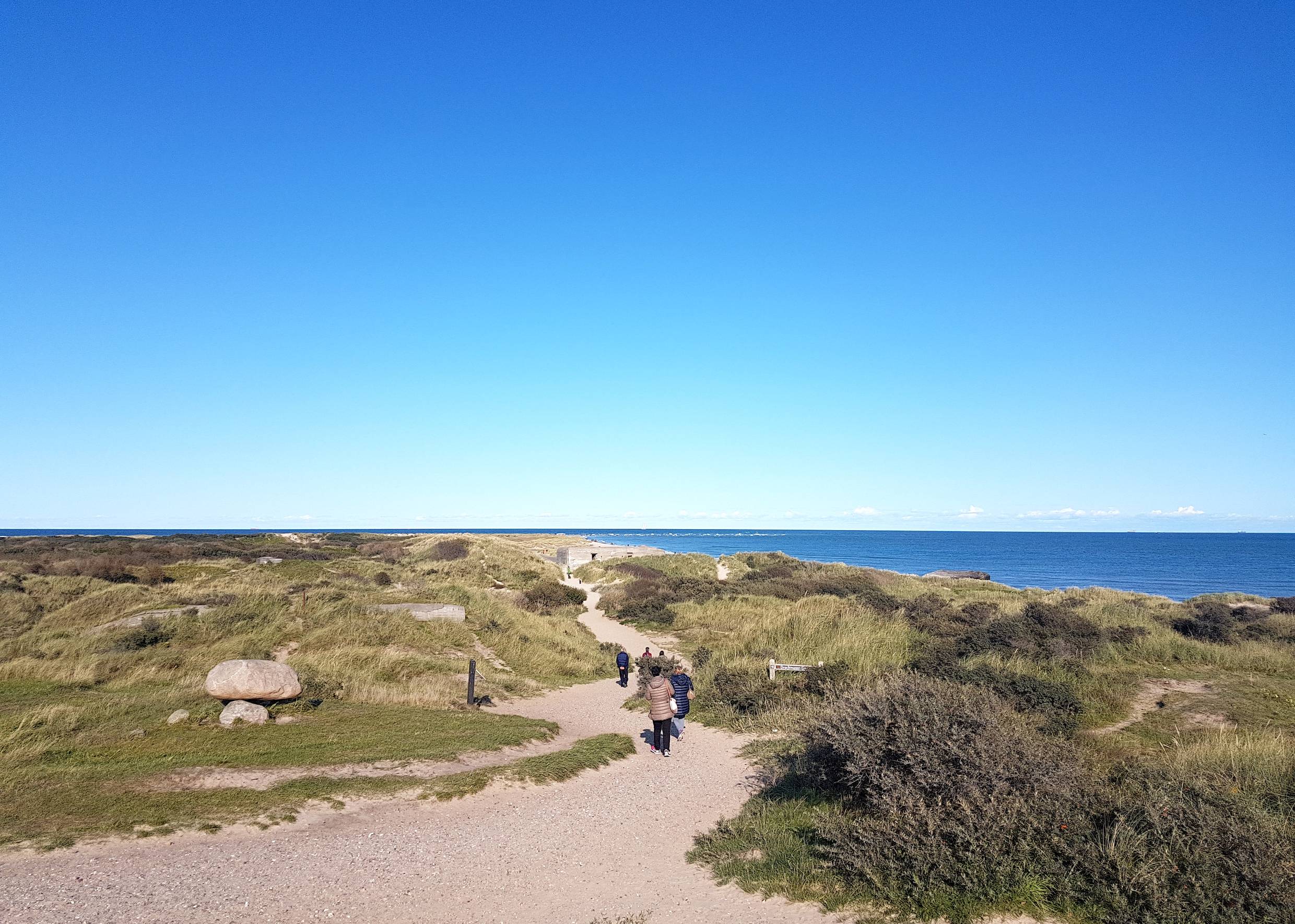 Spaziergänger auf einem Weg in den Dünen am Meer