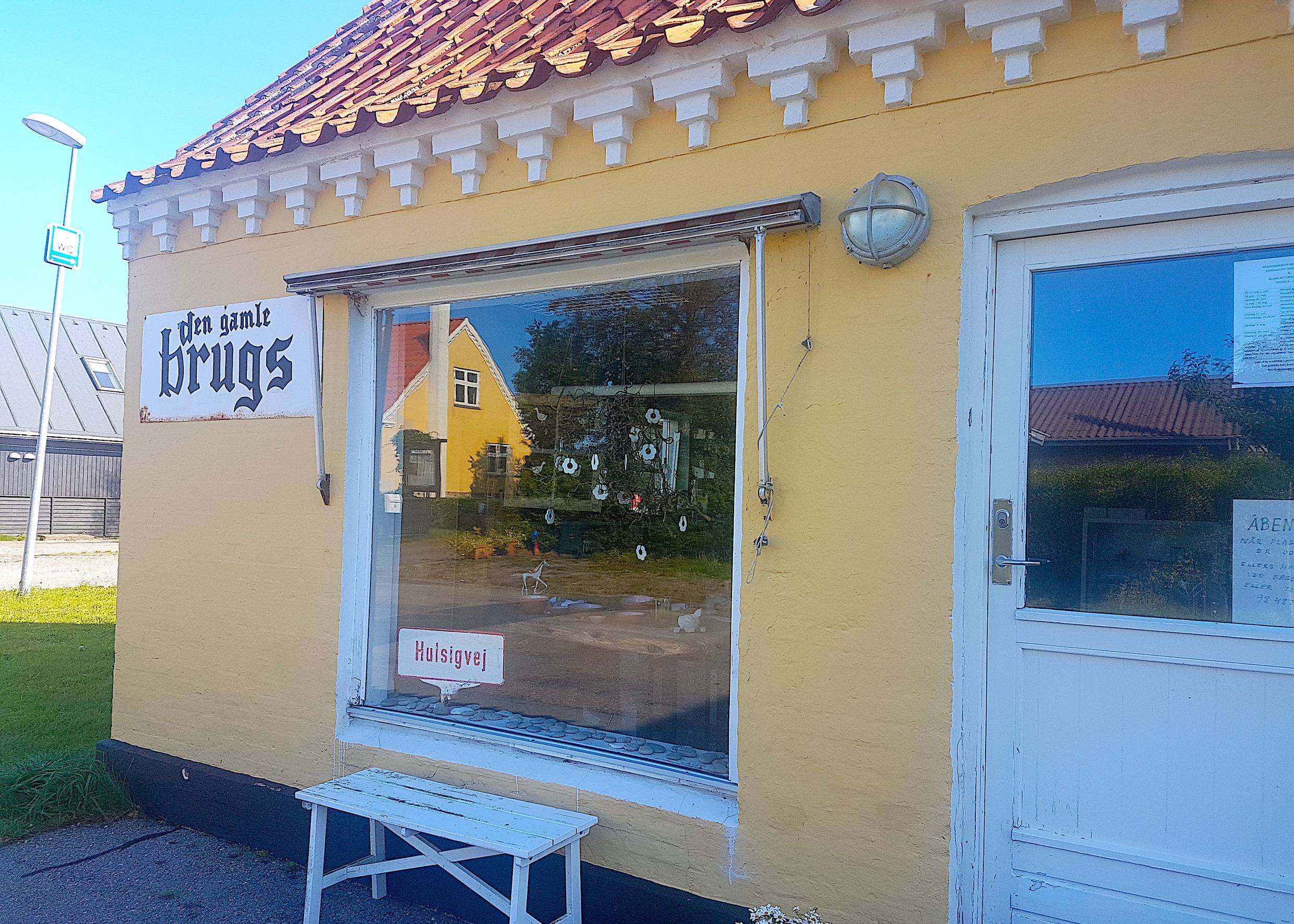 Trödelladen in gelbem Haus mit weißer Bank vor dem Fenster