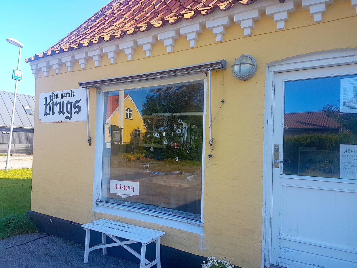 Trödelladen in gelbem Haus mit weißer Bank vor dem Fenster