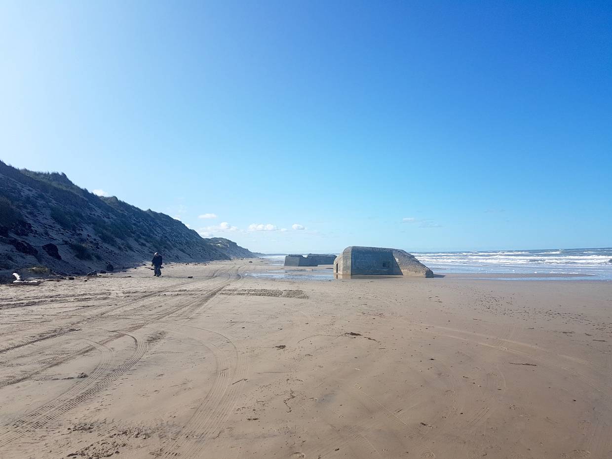 Flacher, steinloster Strand mit einem versinkenden Bunker
