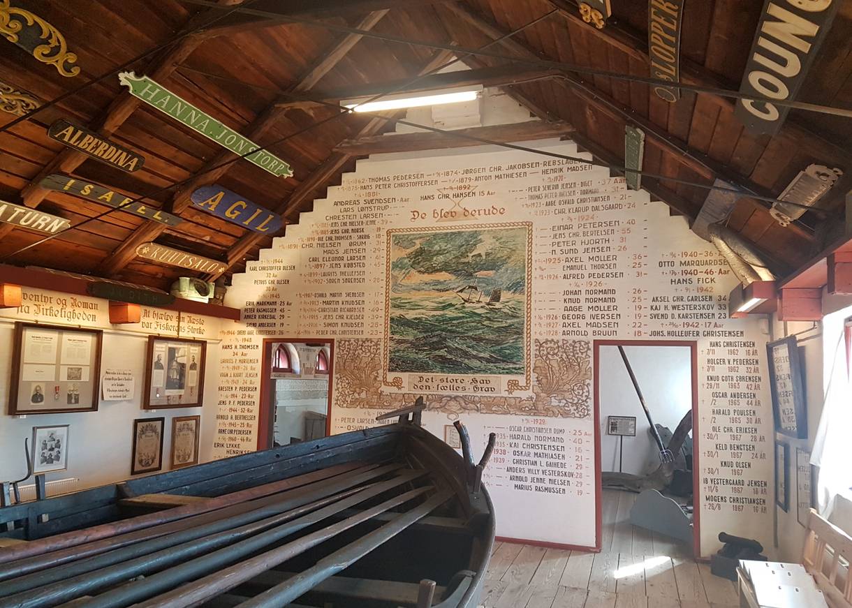 Reich beschrifteter Wand, davor ein Holzboot