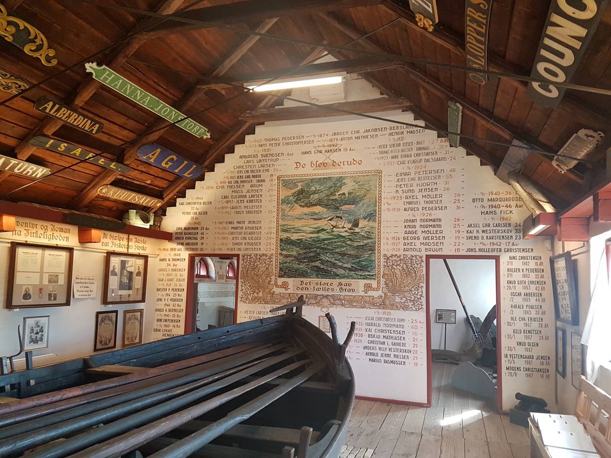Reich beschrifteter Wand, davor ein Holzboot