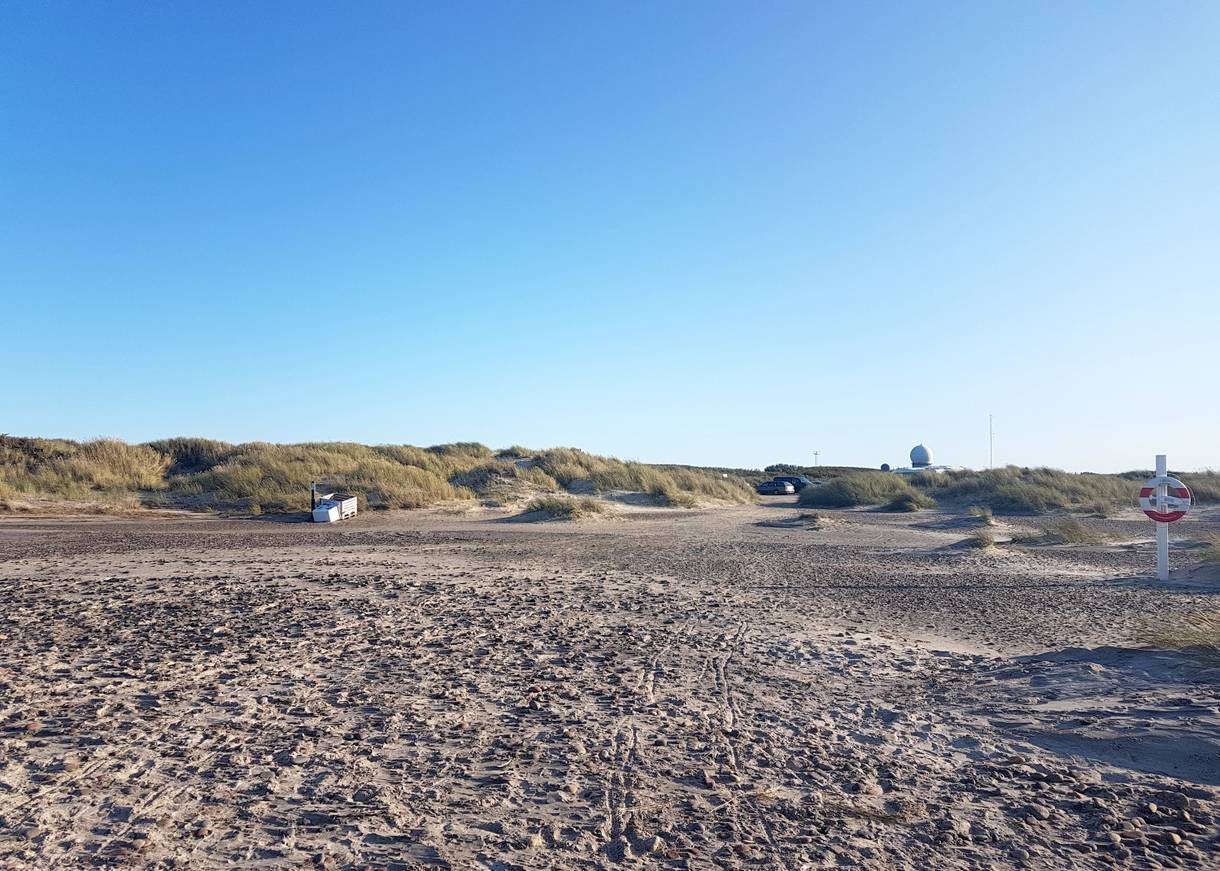 Strandzugang vom Meer aus gesehen, hinter den Dünen eine weiße Kugel, daneben Antennen