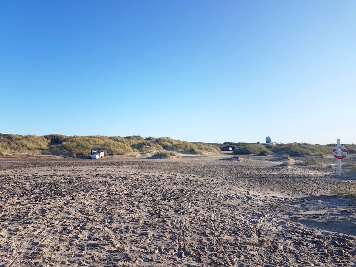 Strandzugang vom Meer aus gesehen, hinter den Dünen eine weiße Kugel, daneben Antennen
