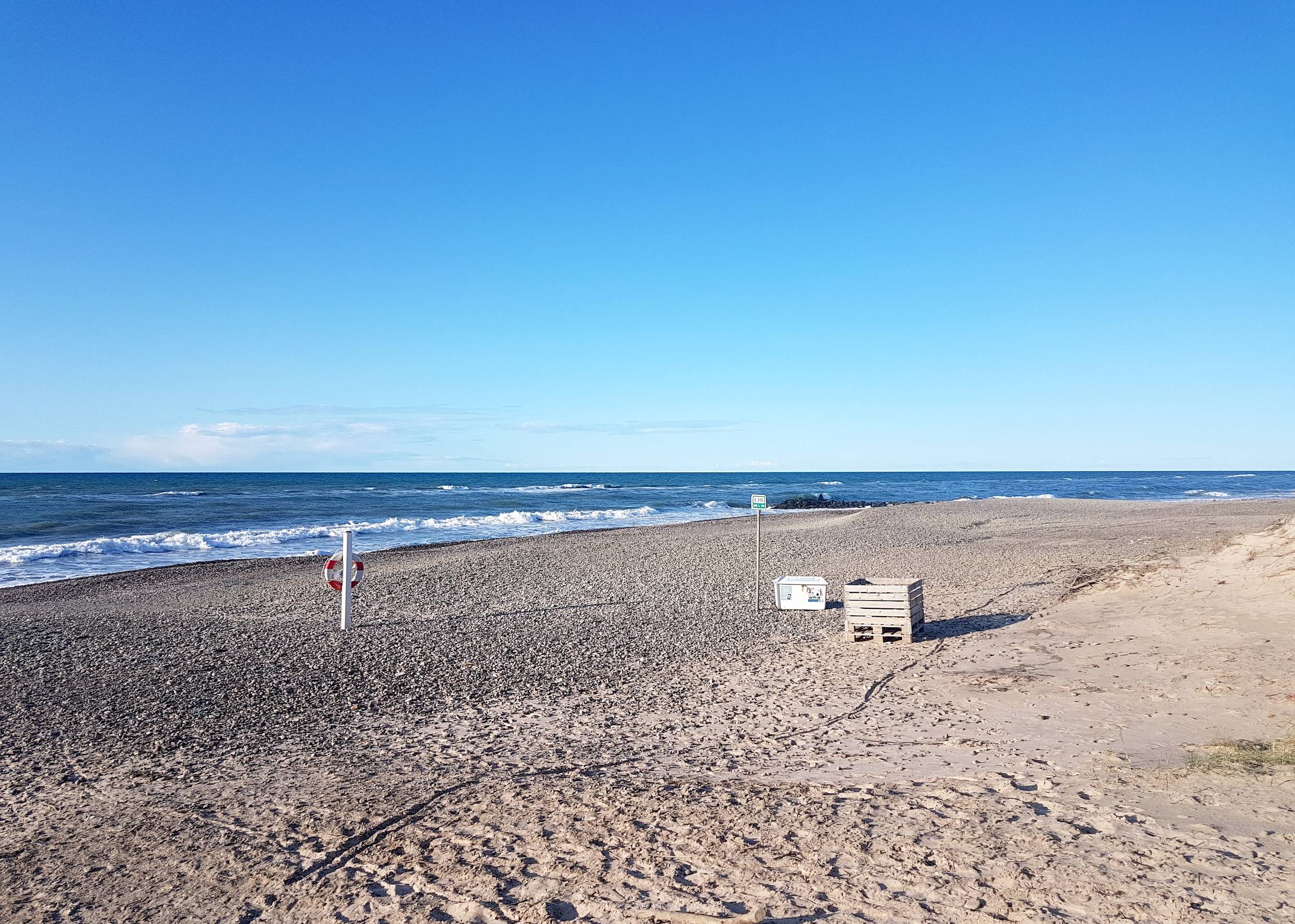 Steiniger Nordseestrand, in der Bildmitte eine Kiste für Strandgut