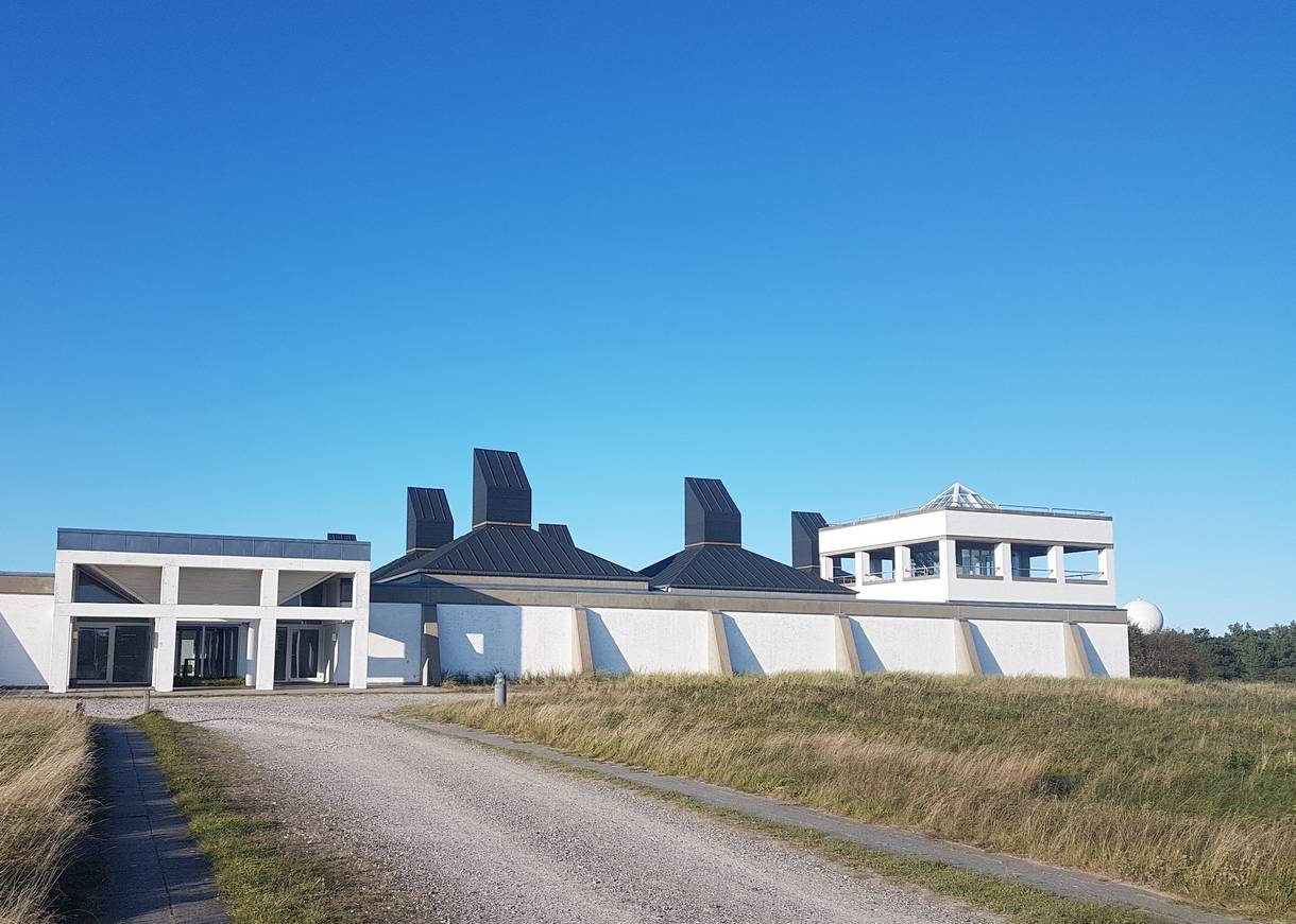 Schotterweg zu einem weißen, modernen Gebäude auf einer Wiese