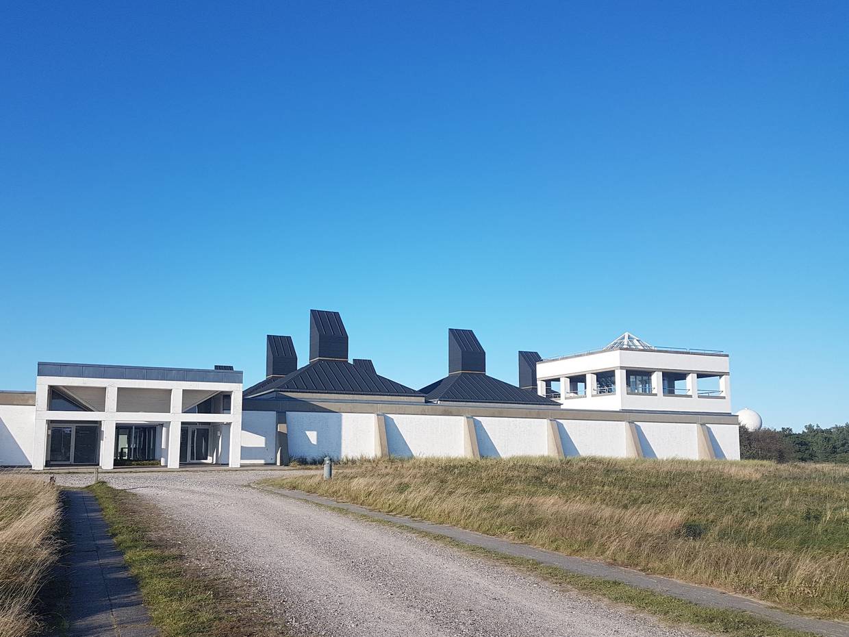Schotterweg zu einem weißen, modernen Gebäude auf einer Wiese