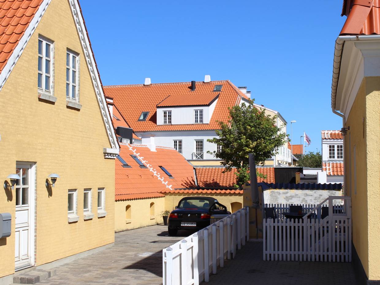 Gelb-weiße Häuser mit rotem Ziegeldach, davor ein weißer Gartenzaun