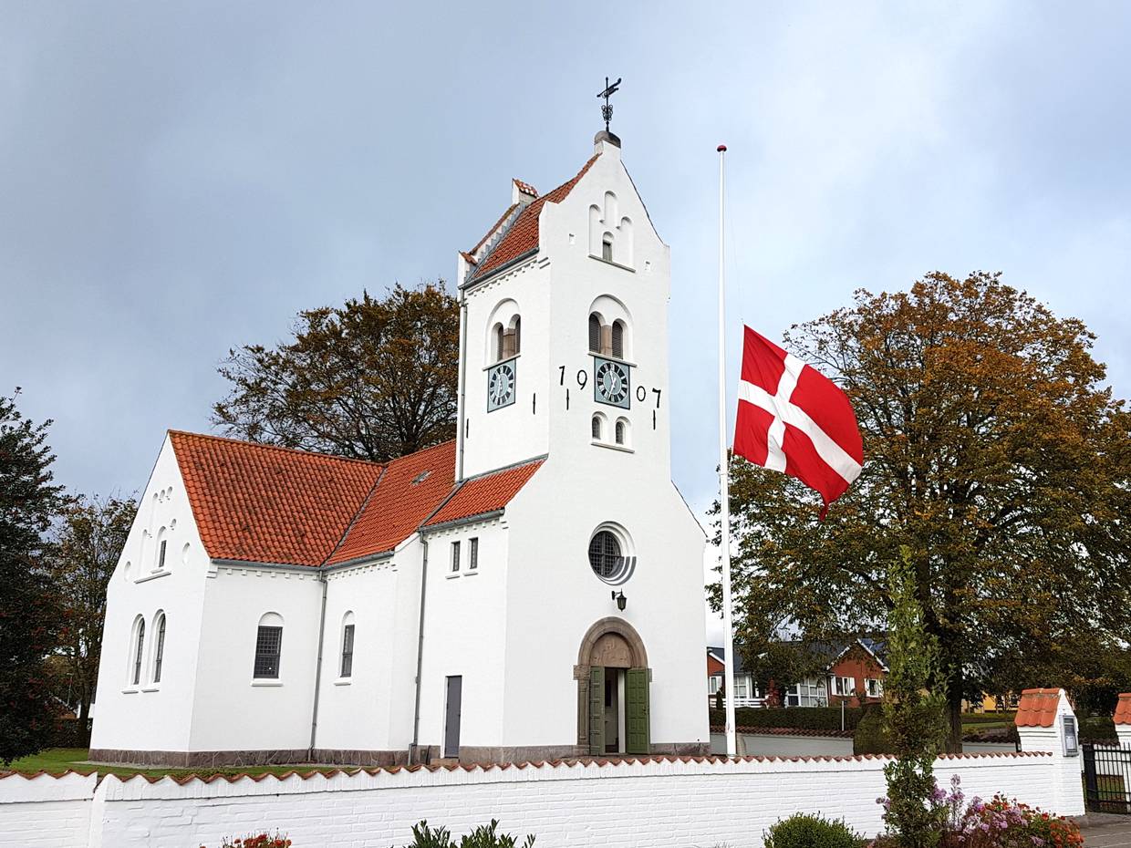 Weiße Kirche, davor eine dänischen Fahne im Wind