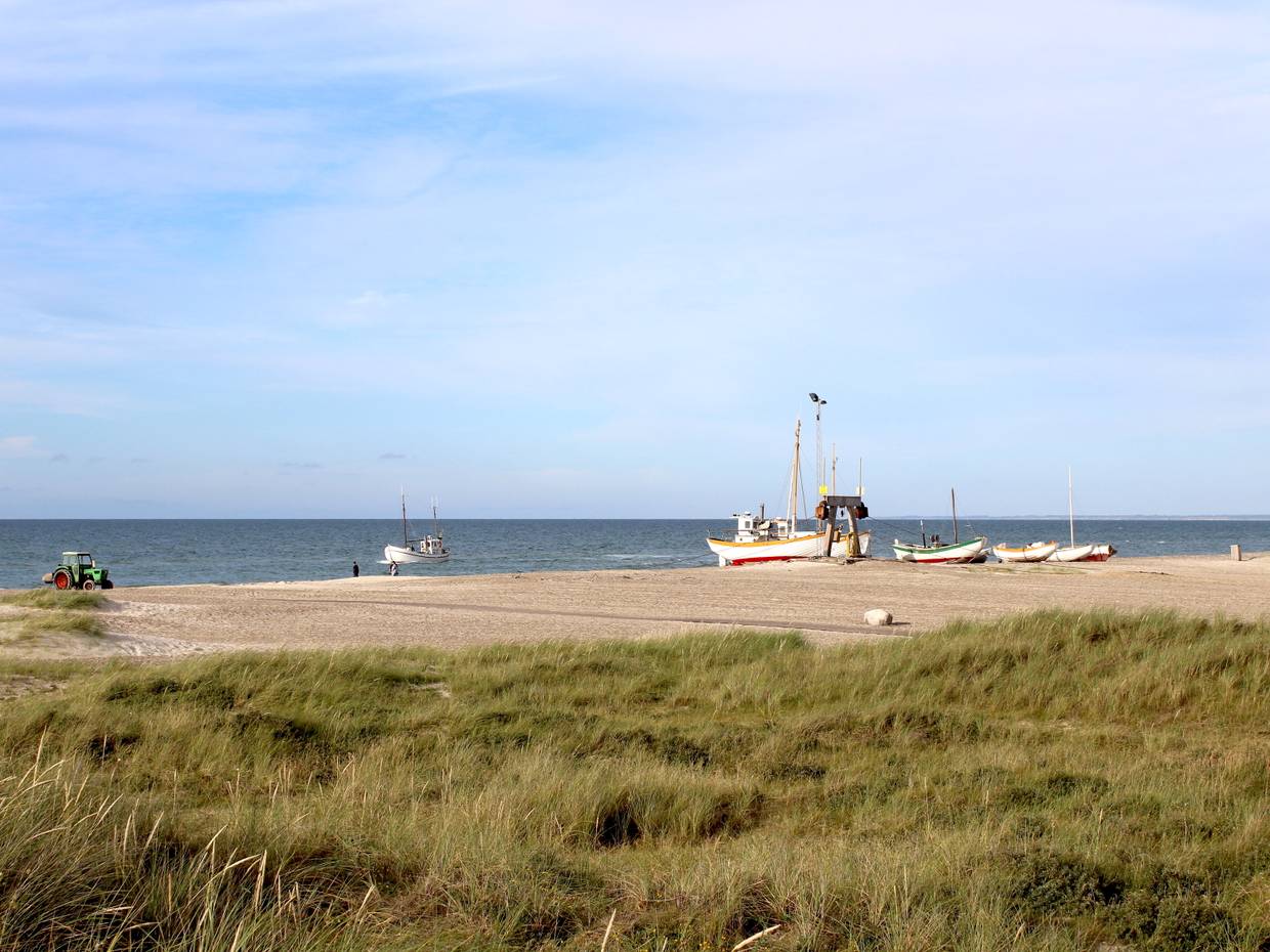 Blick auf weiße Fischerboote und einen Traktor am Strand