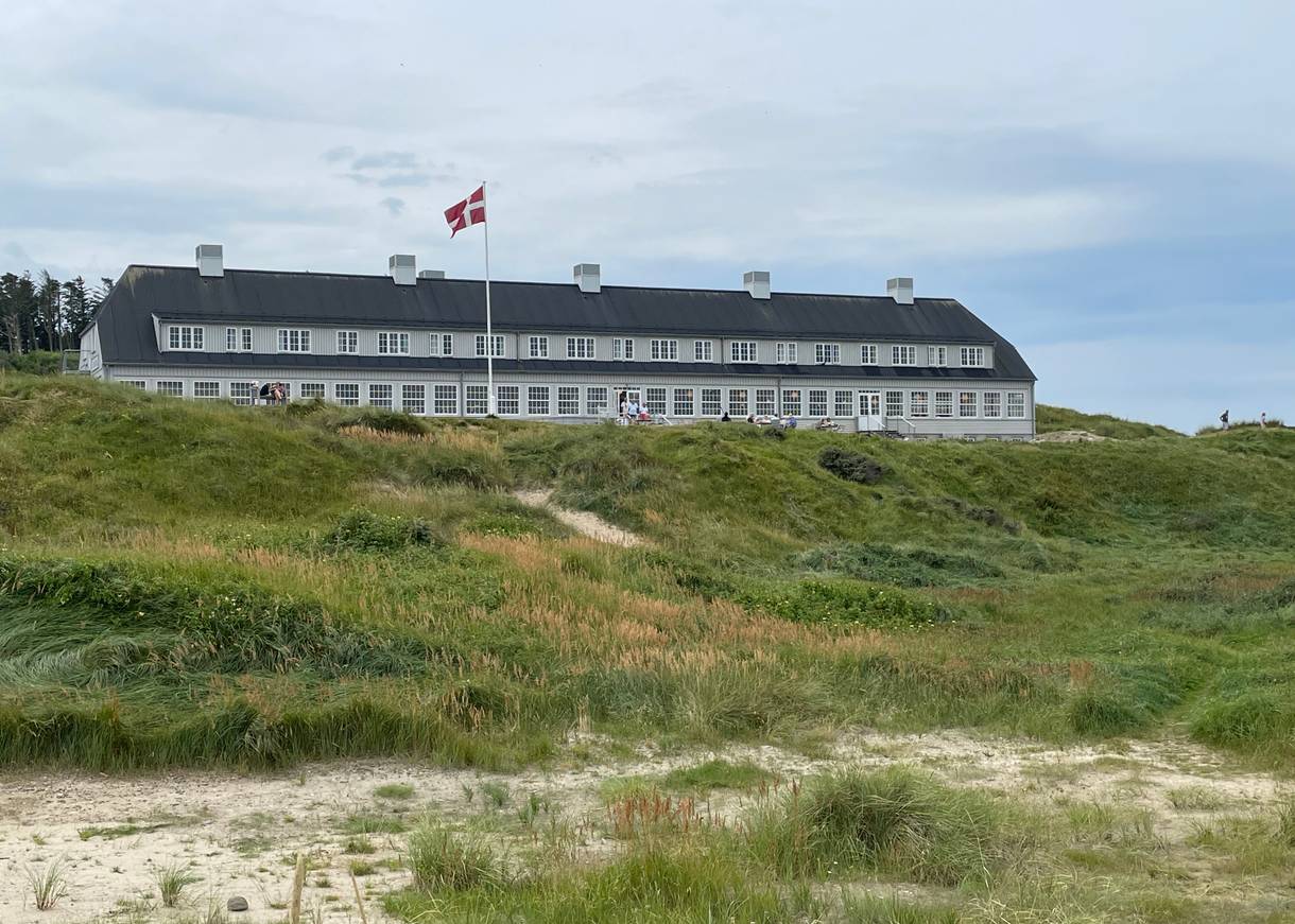Großes Badehotel aus grauem Holz in einer Dünenlandschaft