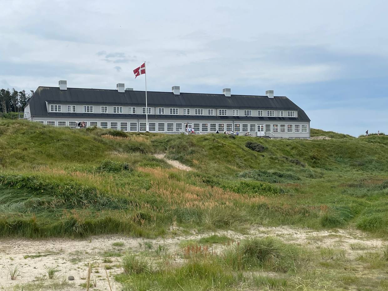 Großes Badehotel aus grauem Holz in einer Dünenlandschaft