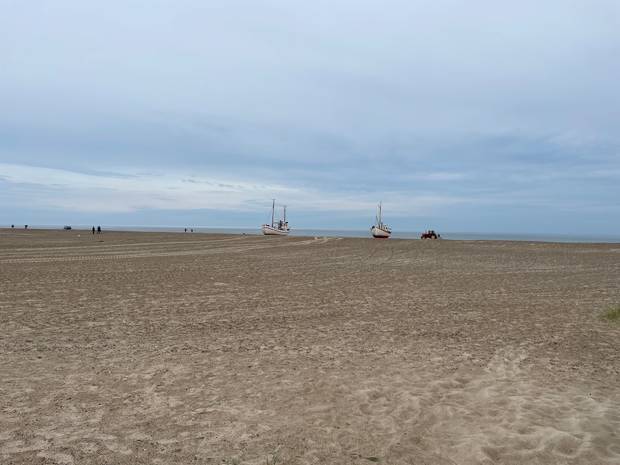 Spaziergänger und Klinkerboote am Slettestrand