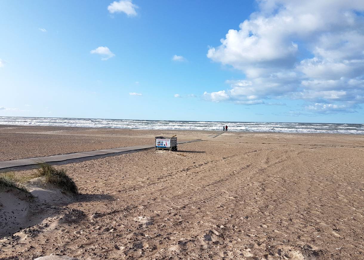 Breiter Strand mit einem befestigten Weg zum Wasser