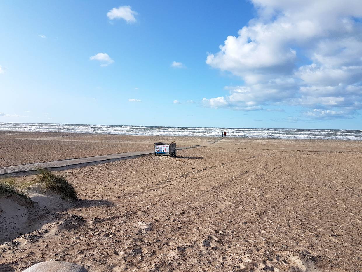 Breiter Strand mit einem befestigten Weg zum Wasser