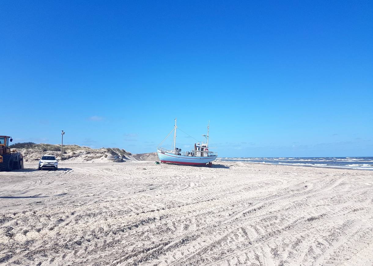 Fischerboot auf einem menschenleeren, breiten Strand