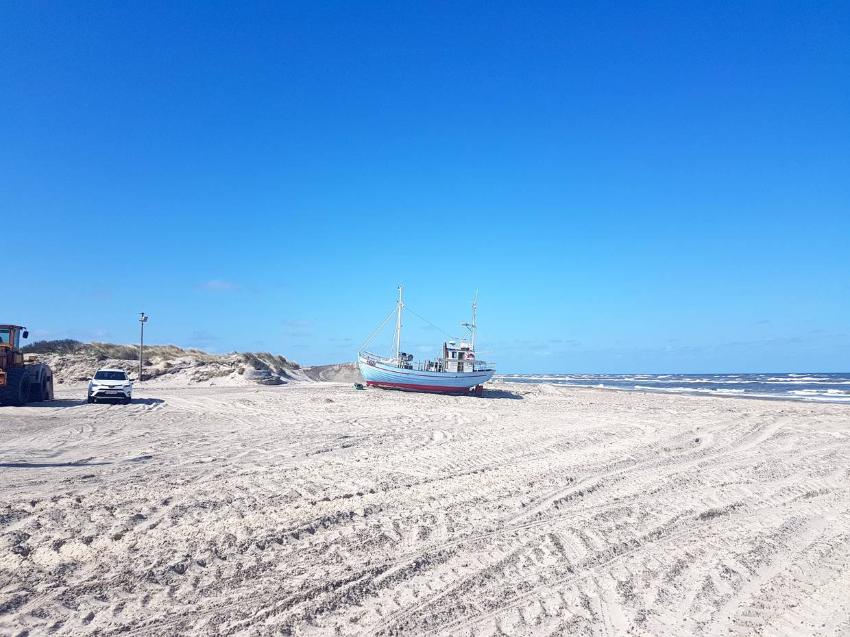 Fischerboot auf einem menschenleeren, breiten Strand
