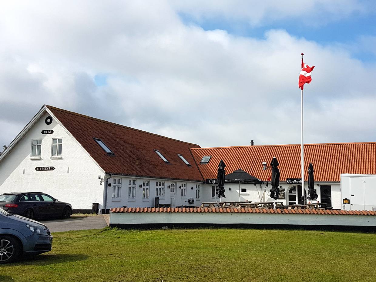 Weißer Bauernhof mit einer Restaurantterrasse und Dannebrog vor der Tür