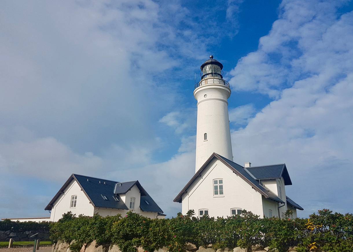 Weißer Leuchtturm mit zwei identischen Nebengebäuden