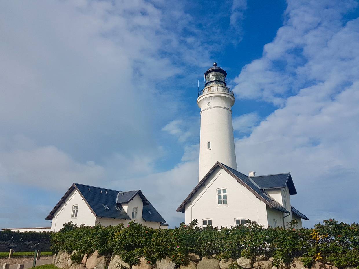 Weißer Leuchtturm mit zwei identischen Nebengebäuden