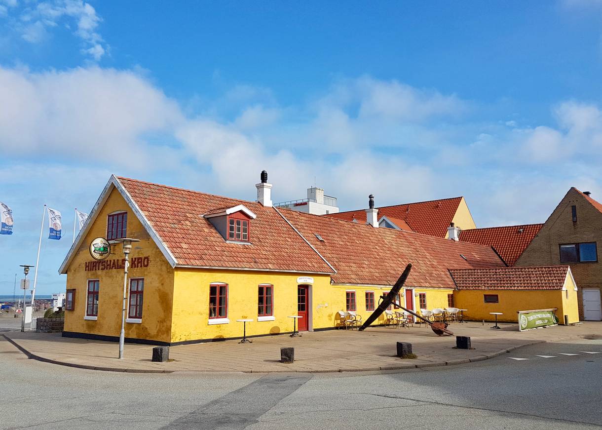 Hirtshals Kro, ein gelbes Gasthaus mit Hafenblick
