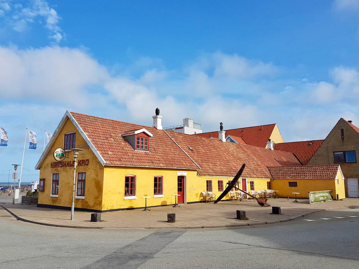 Hirtshals Kro, ein gelbes Gasthaus mit Hafenblick