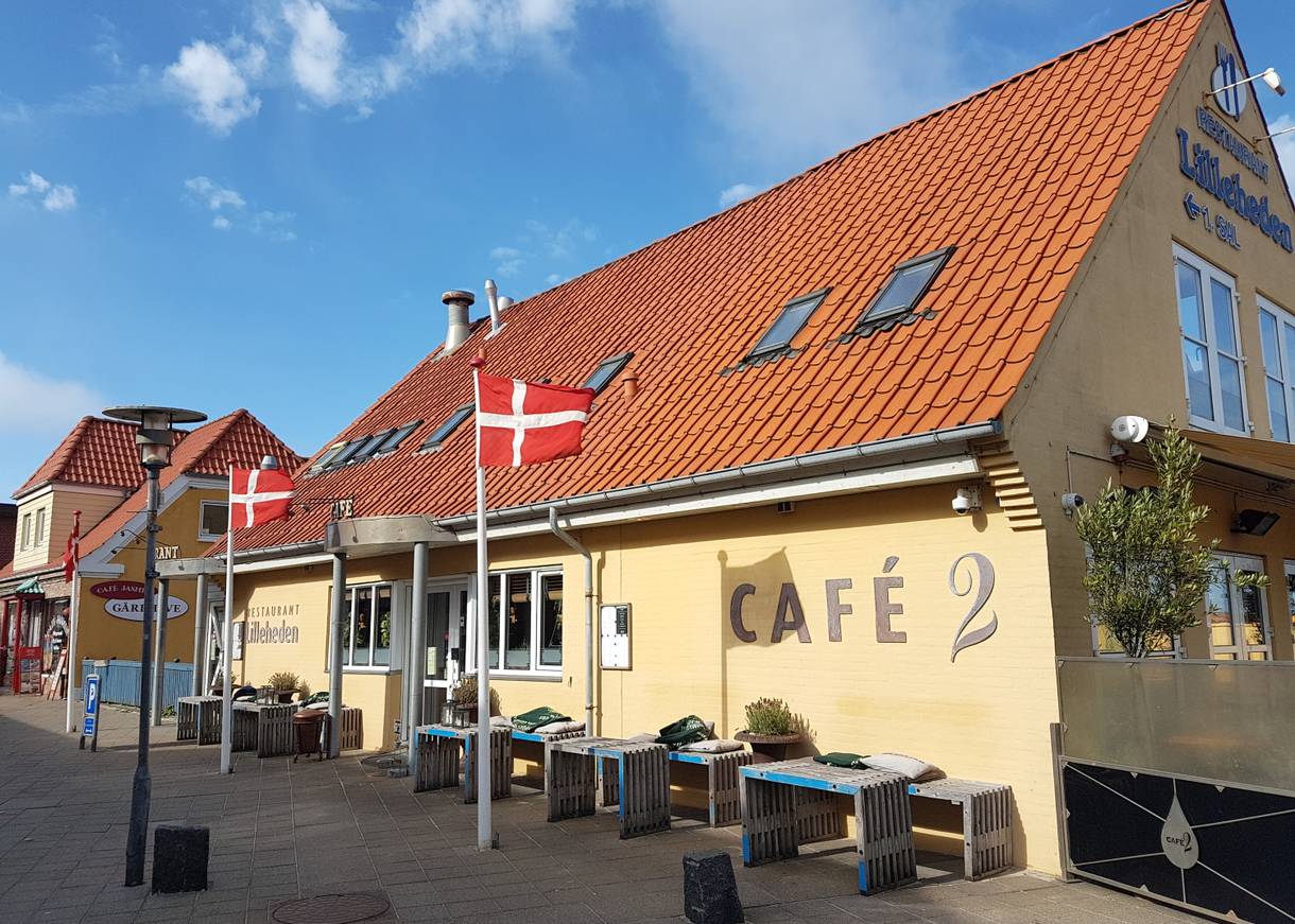 Gelbes Haus mit einem Café, Dannebrog und Holzbänke vor der Tür