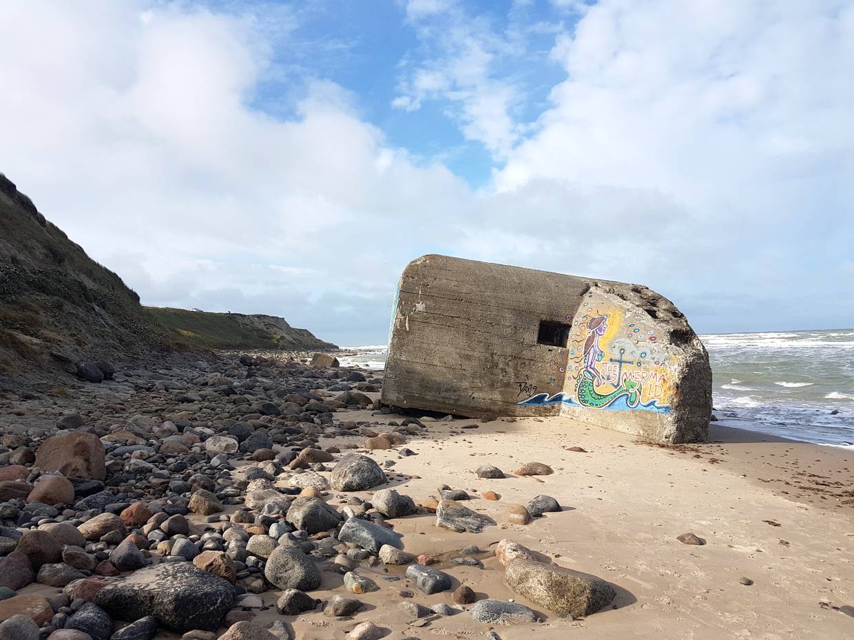 Strand unterhalb von hohen Dünen mit bemalten Bunkern