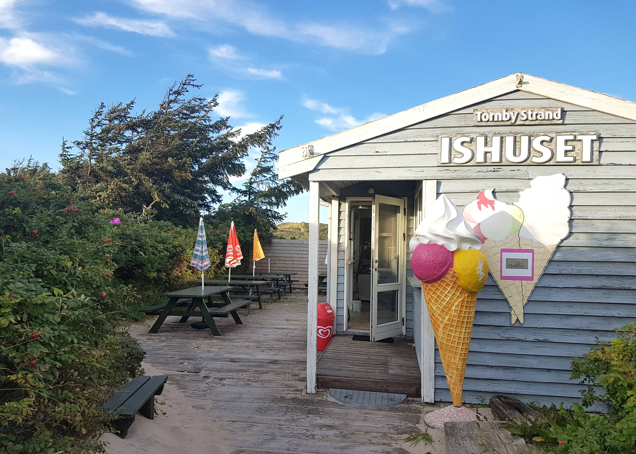 Kleine Holzhütte mit einer Eisdiele, davor eine große Eistüte als Aufsteller