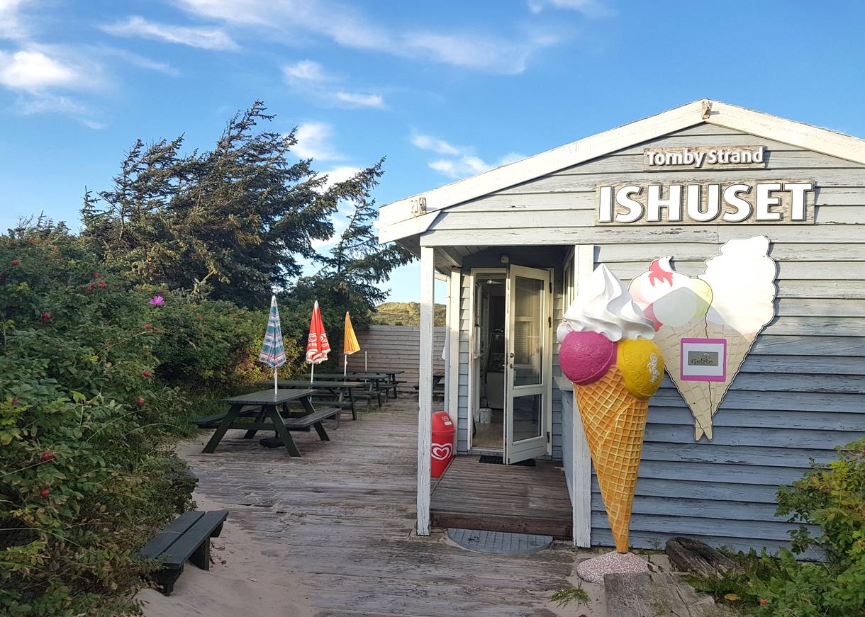 Kleine Holzhütte mit einer Eisdiele, davor eine große Eistüte als Aufsteller