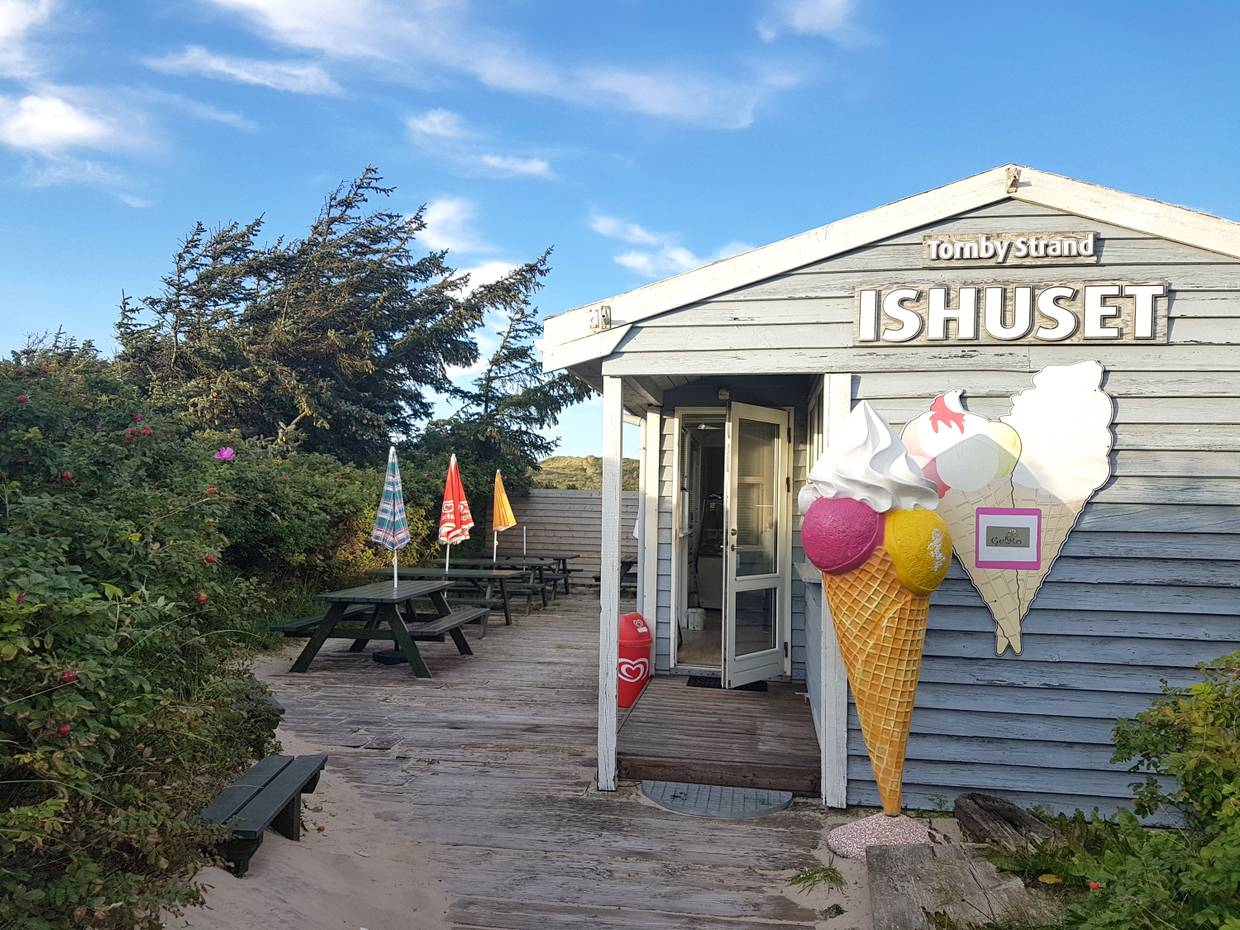 Kleine Holzhütte mit einer Eisdiele, davor eine große Eistüte als Aufsteller