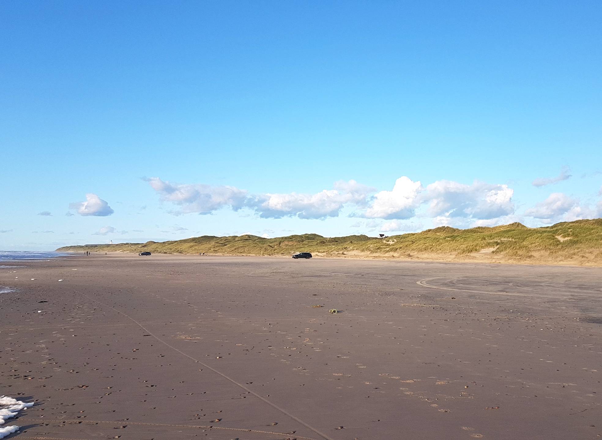 Blick über den Strand in der Abendsonne, im Hintergrund Dünen