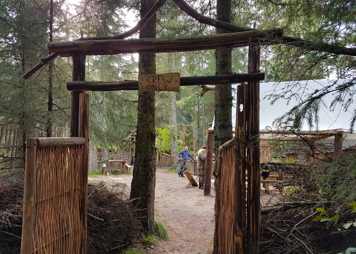 Blick durch ein Holztor auf Mitarbeiter eines Naturprojektes