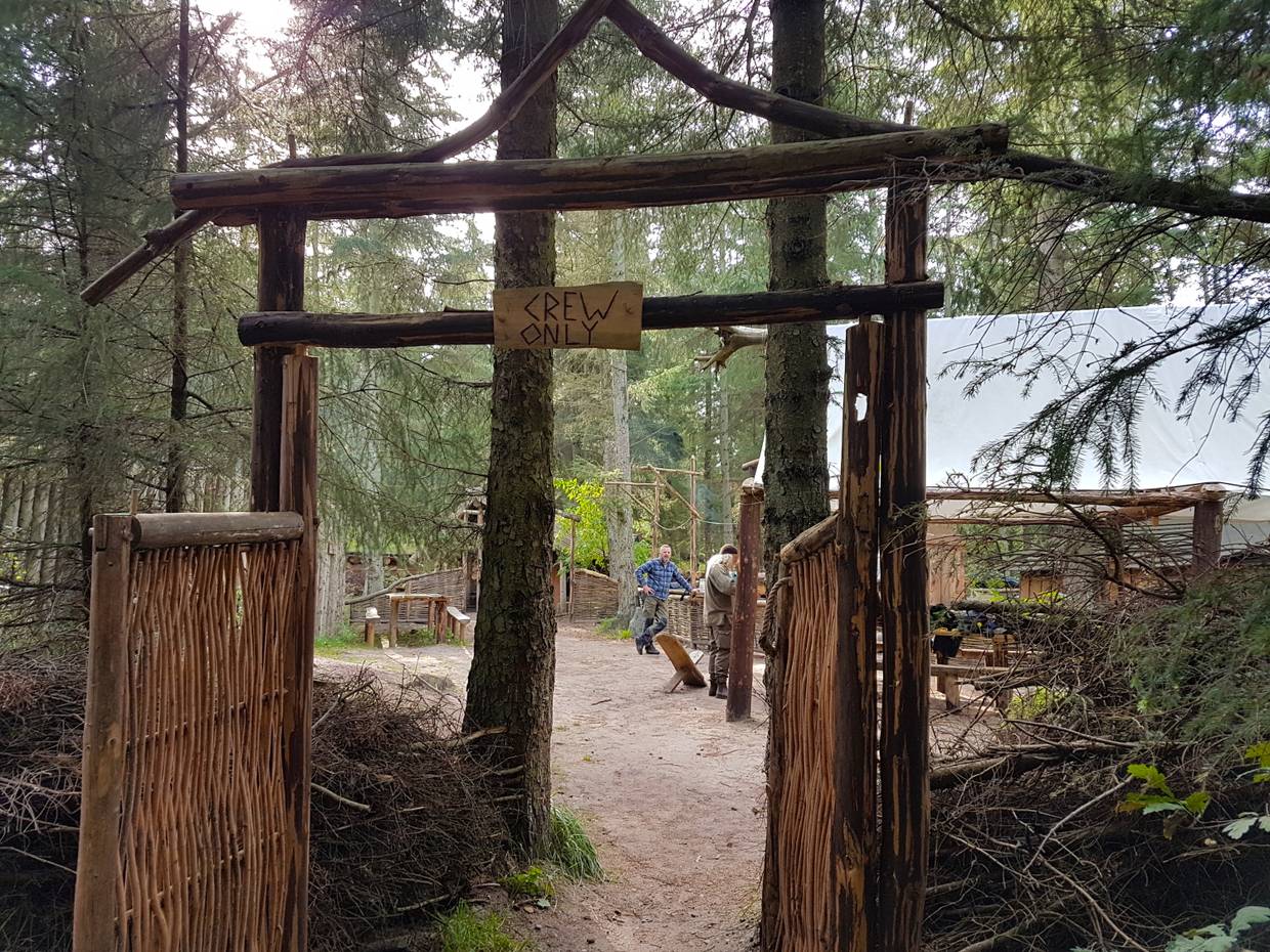 Blick durch ein Holztor auf Mitarbeiter eines Naturprojektes