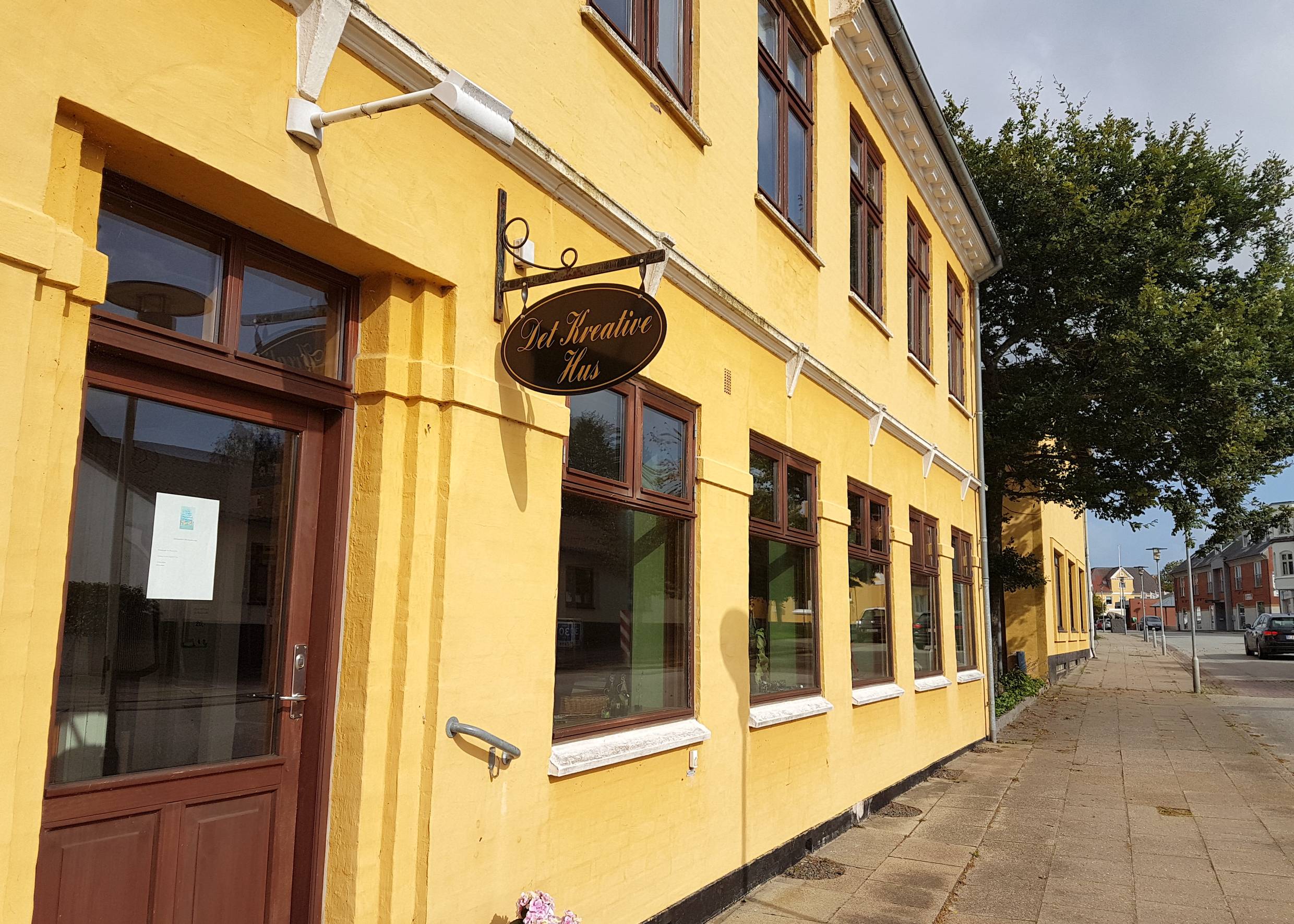 Gelbes Haus an der Straße mit kleinen Schaufenstern