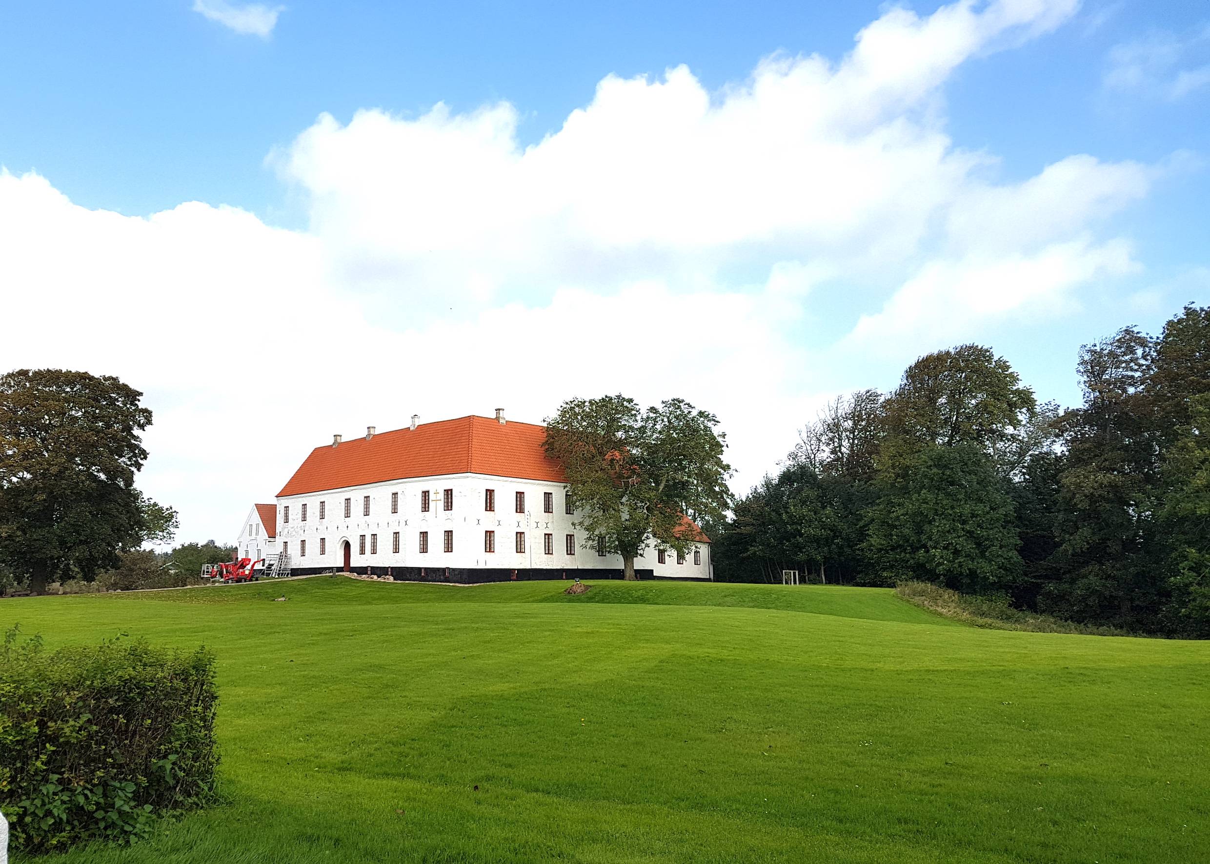 Kleines, weißes Herrenhaus, umgeben von sattgrünem Rasen
