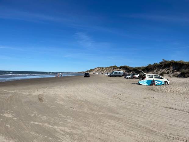 Sandstrand mit parkenden Autos an den hohen Dünen
