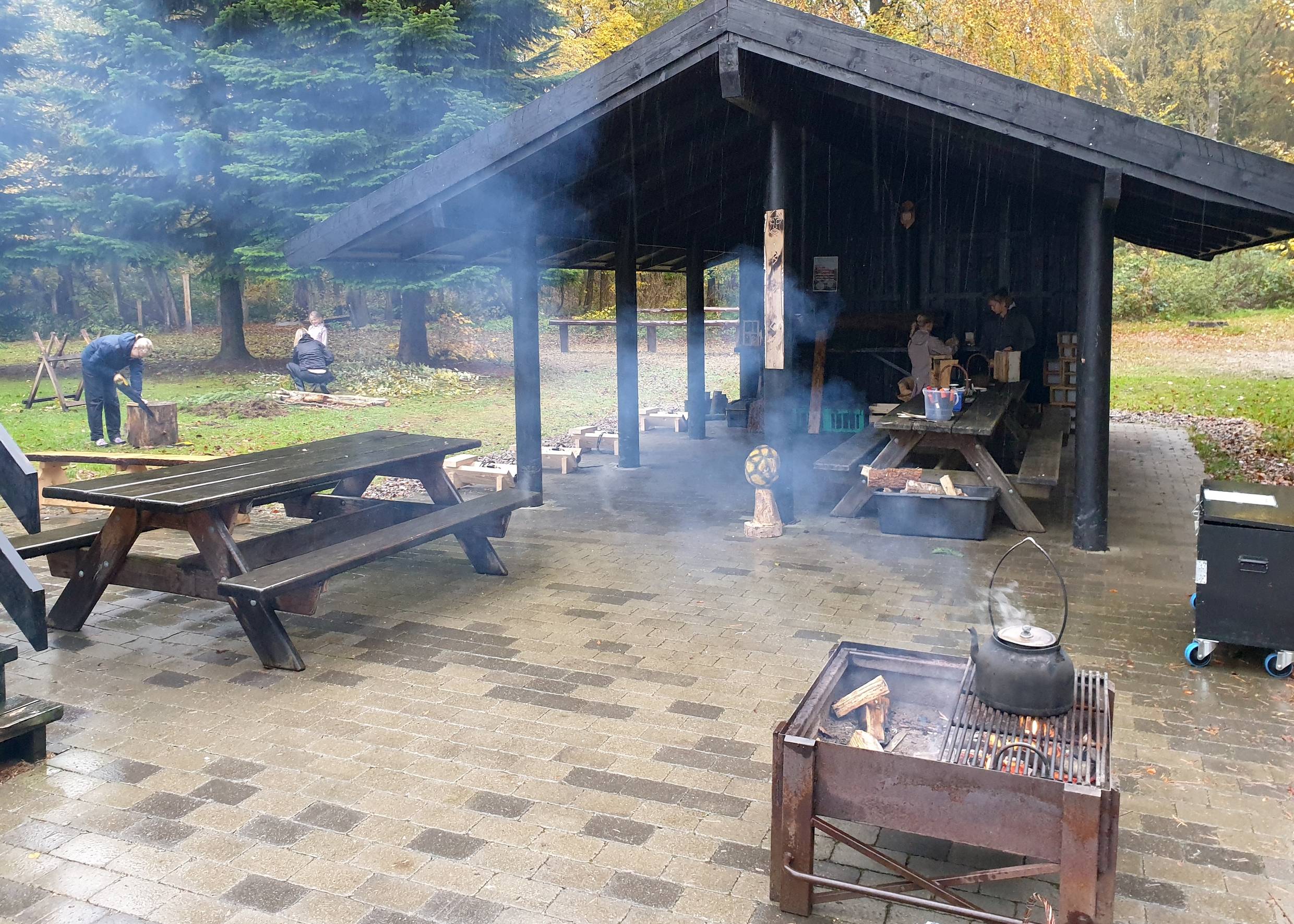 Offene Picknickhütte, davor ein qualmender Grill