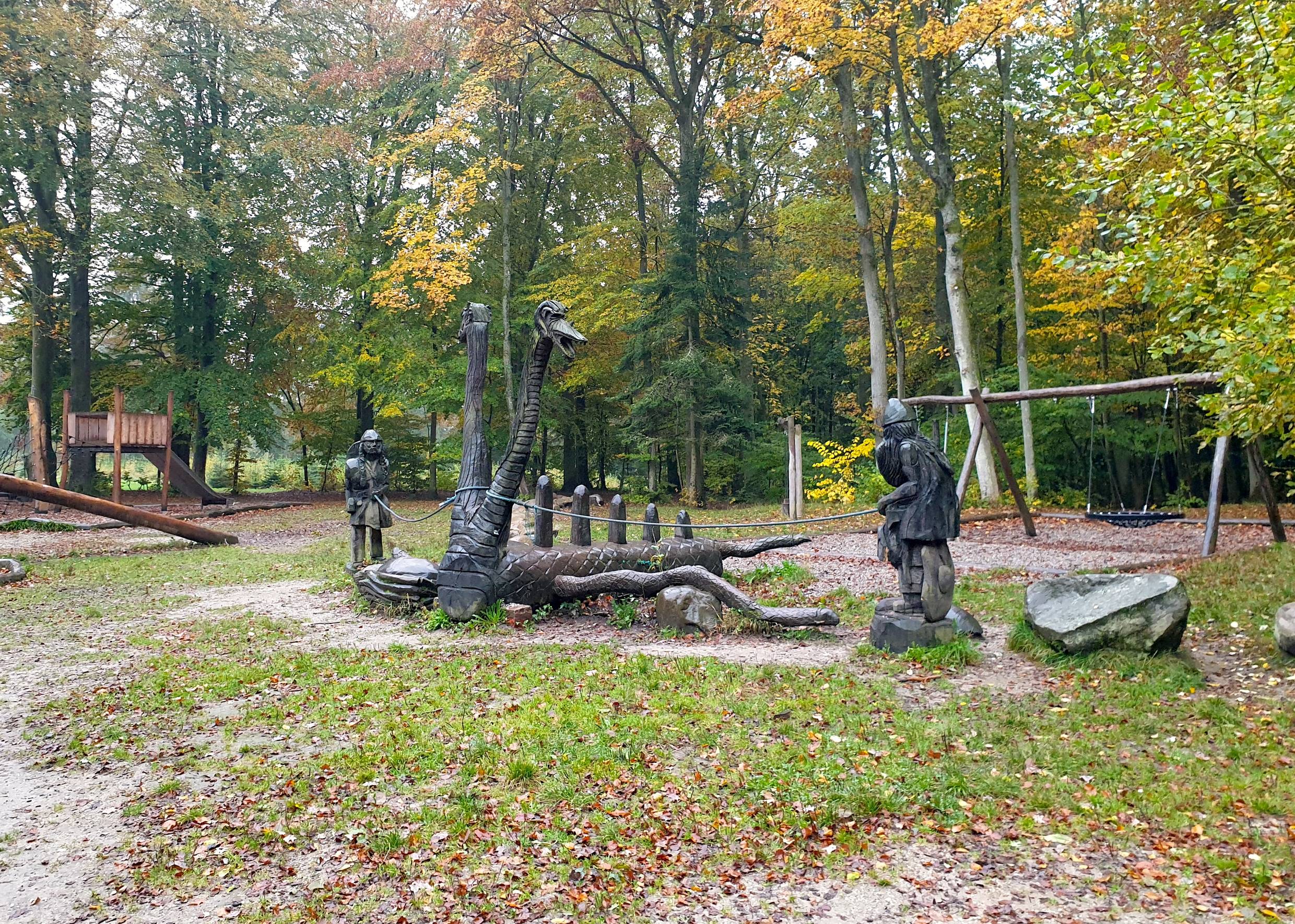 Geschnitzte Holzfiguren auf einem Waldspielplatz im Herbst