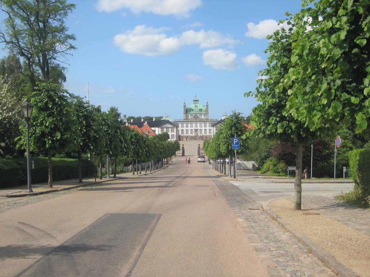 Weißes Schloss mit grünem Kupferdach am Ende einer Allee