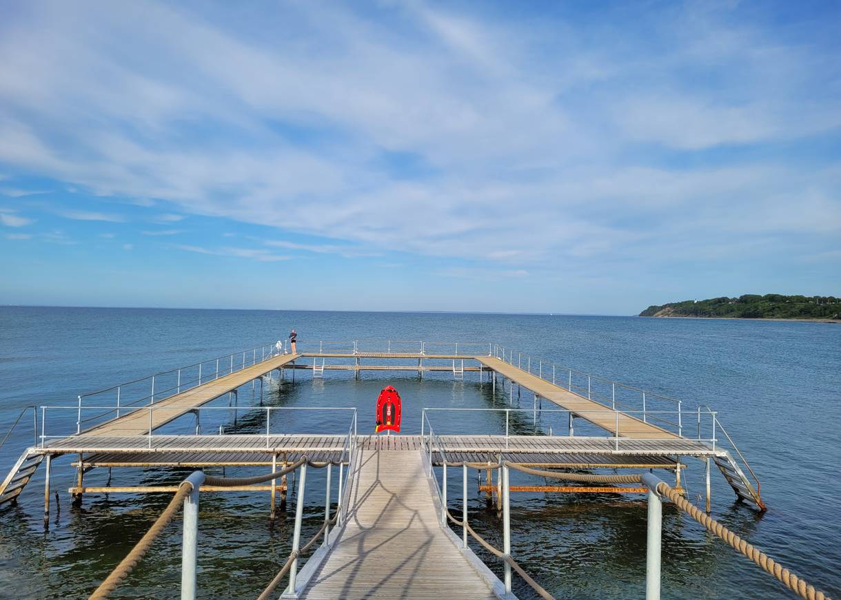 Im Viereck gebauter Badesteg, in Gilleleje im Hintergrund grüne Küste