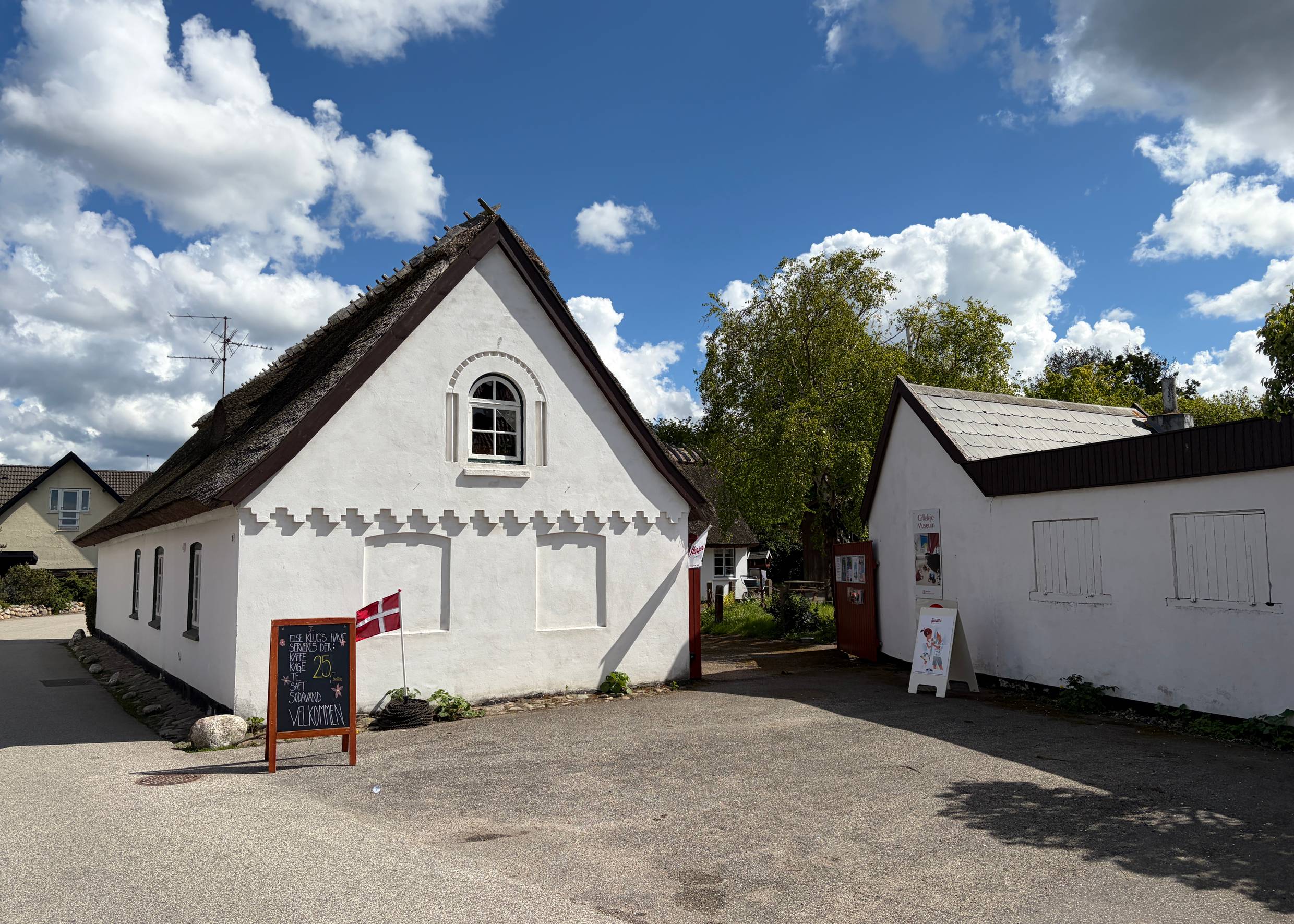 Museum in einem, weißen Reetdachhaus mit Blick in einem Innenhof, davor ein Schild mit Dannebrog