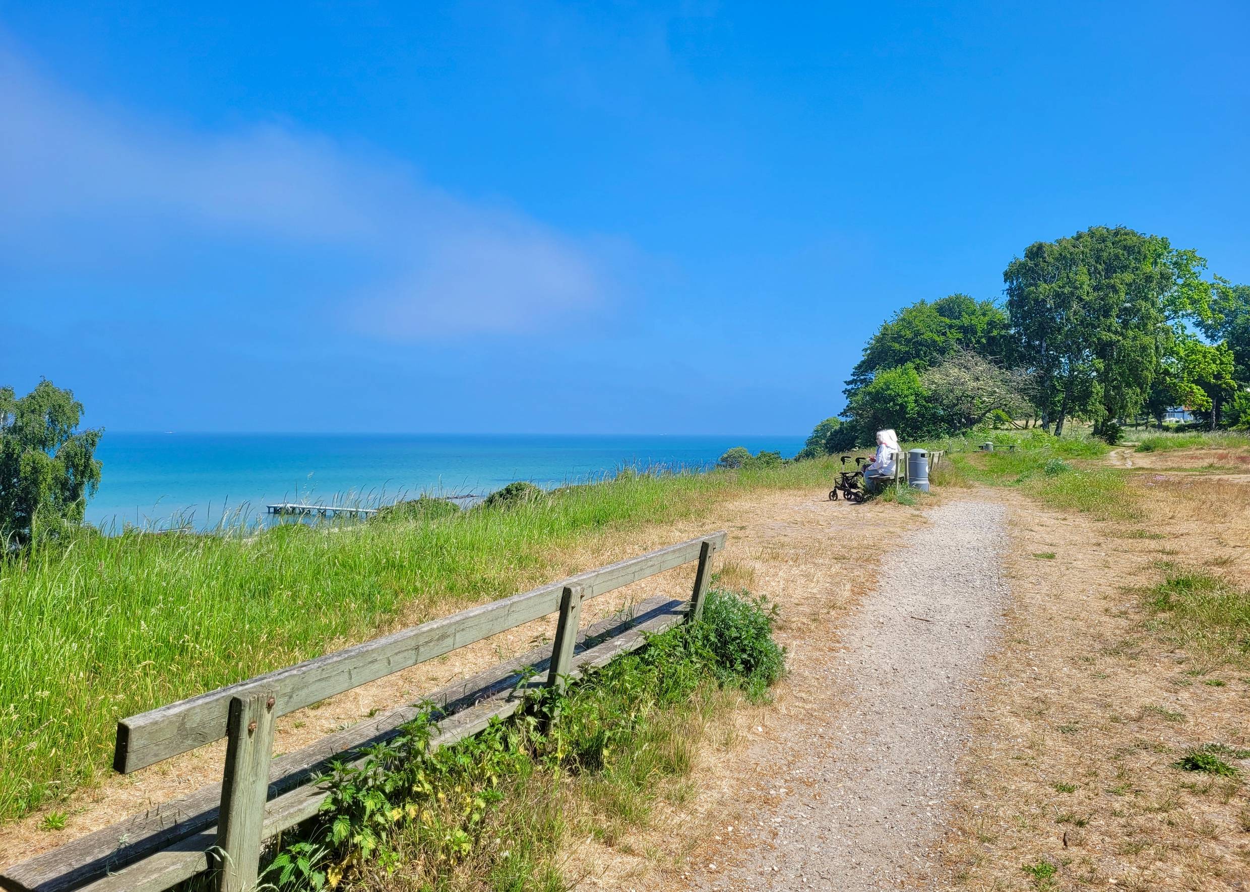 Fußweg an der Küste mit Bänken und Meerblick