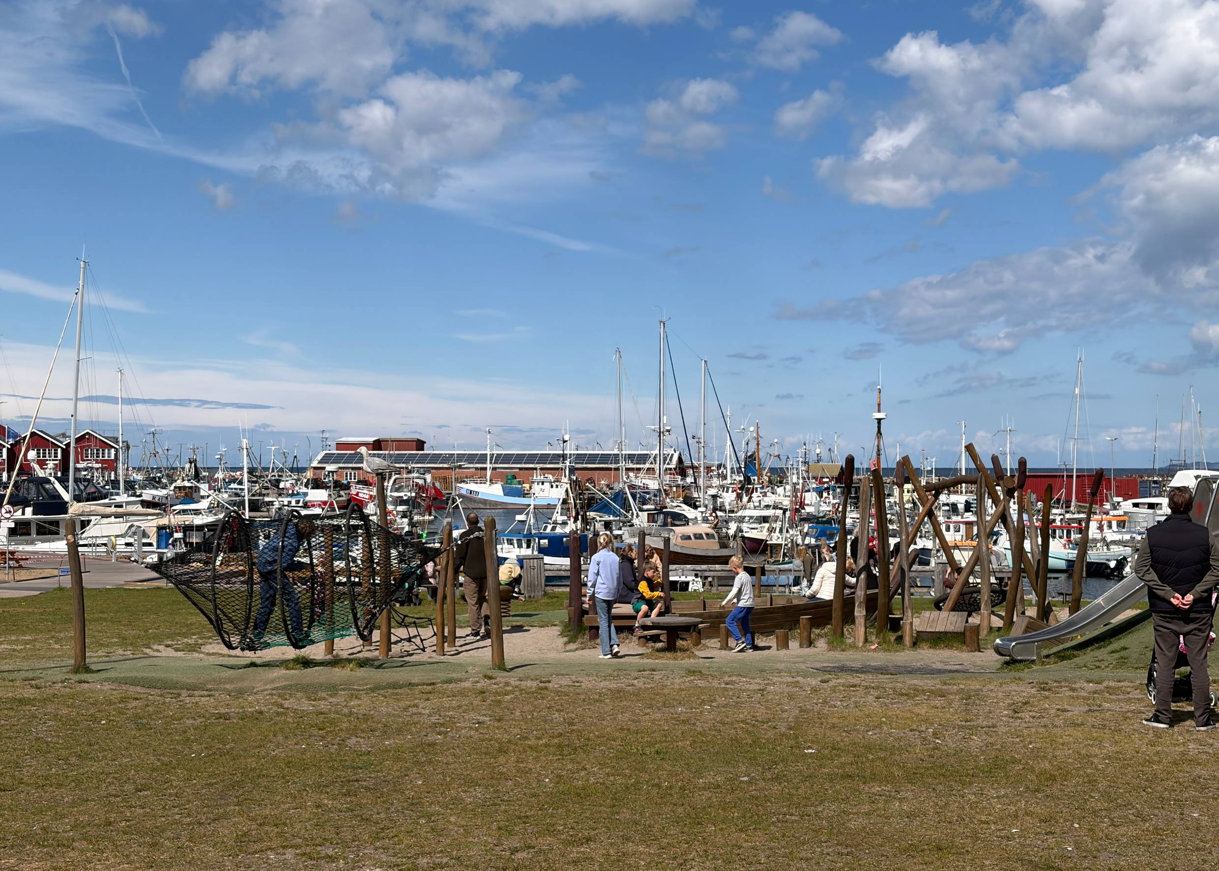 Spielplatz, dahinter Segelboote und Hafen gebäude