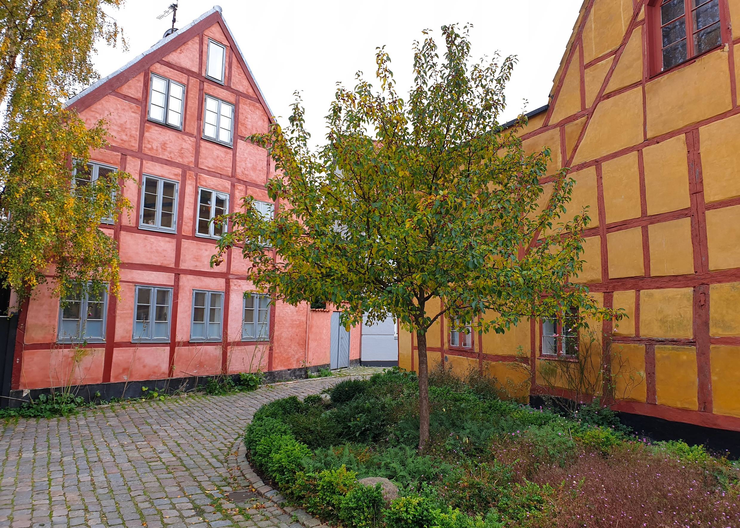 Gelbes und hellrotes große Fachwerkhaus an einer Kopfsteinpflastergasse