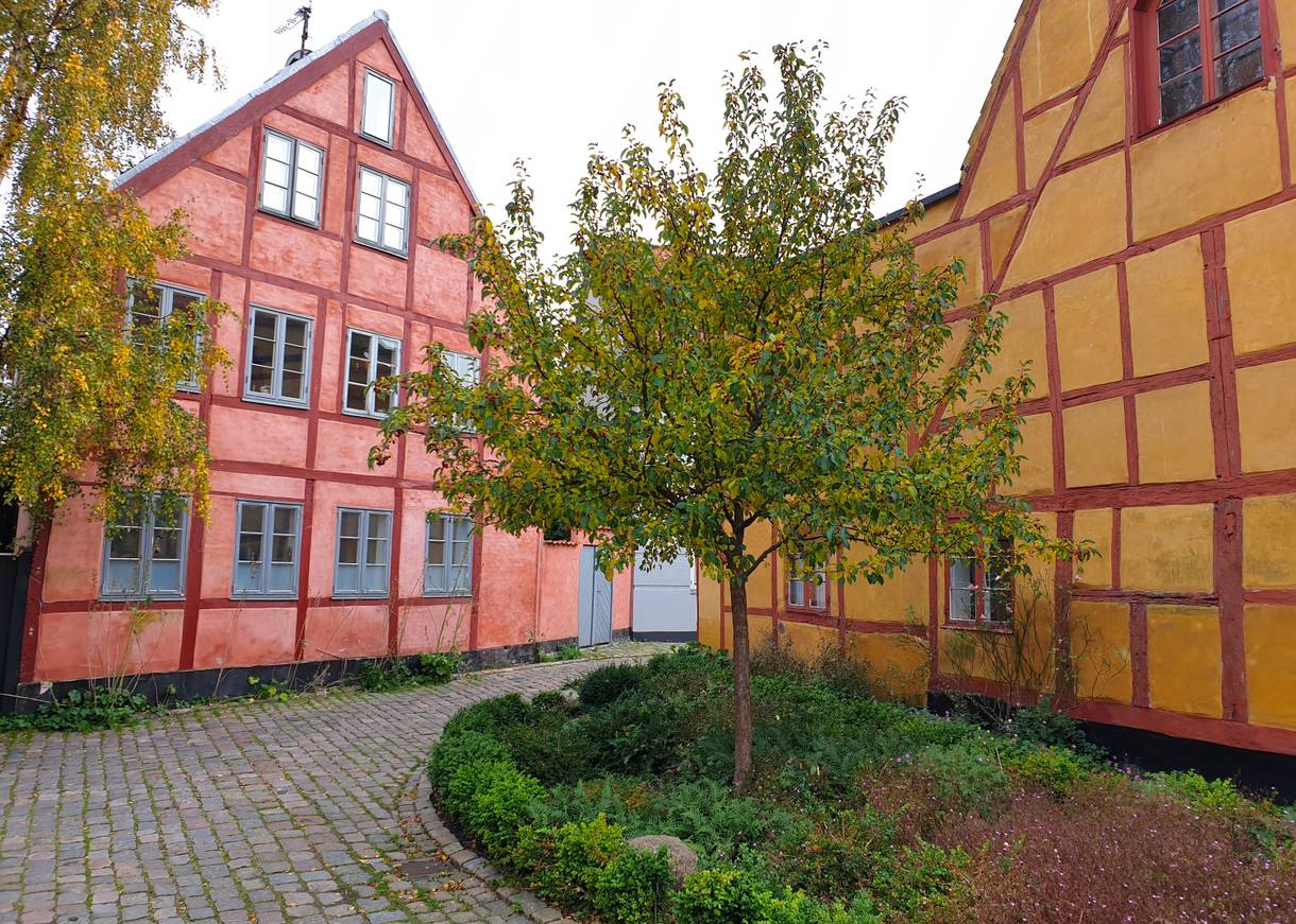 Gelbes und hellrotes große Fachwerkhaus an einer Kopfsteinpflastergasse