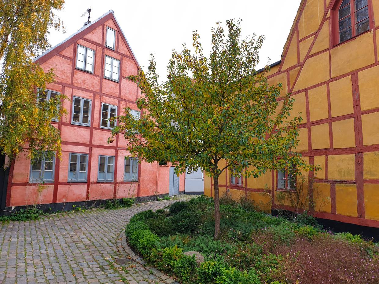 Gelbes und hellrotes große Fachwerkhaus an einer Kopfsteinpflastergasse