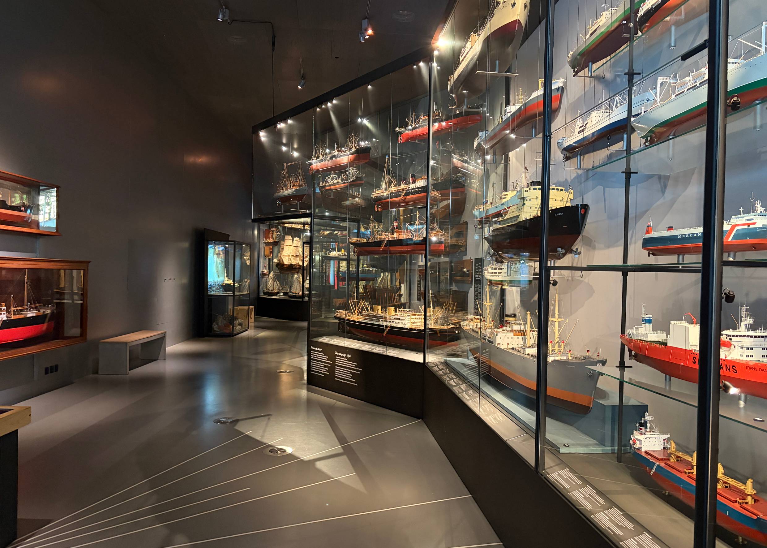 Mehrere Vitrinen in einem dunklen Museumsraum mit Containerschiffen
