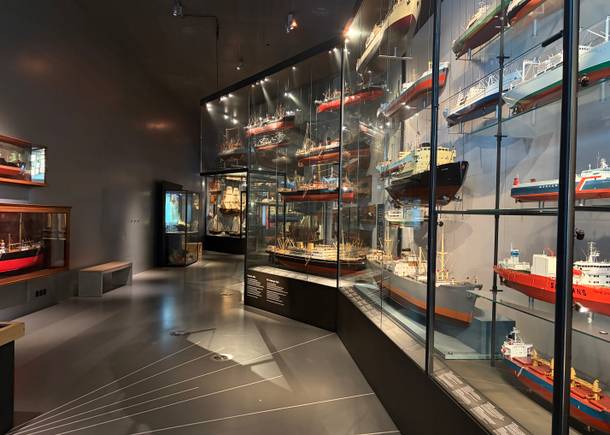 Mehrere Vitrinen in einem dunklen Museumsraum mit Containerschiffen