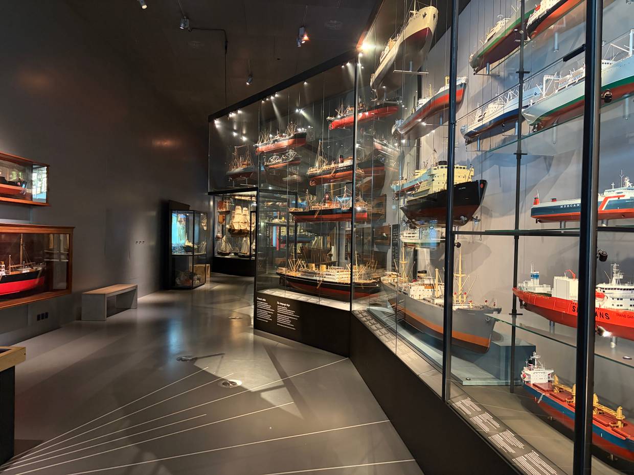 Mehrere Vitrinen in einem dunklen Museumsraum mit Containerschiffen